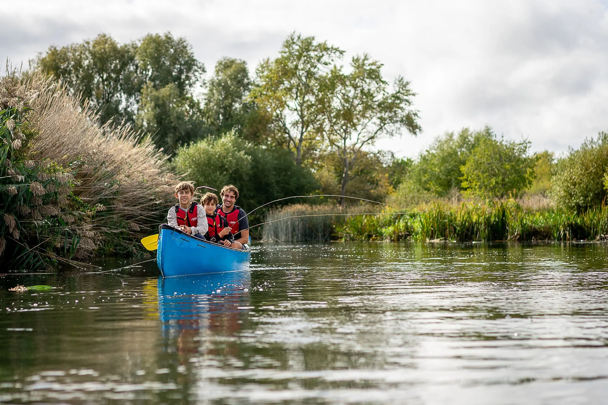 A group paddling a blue canoe on the river