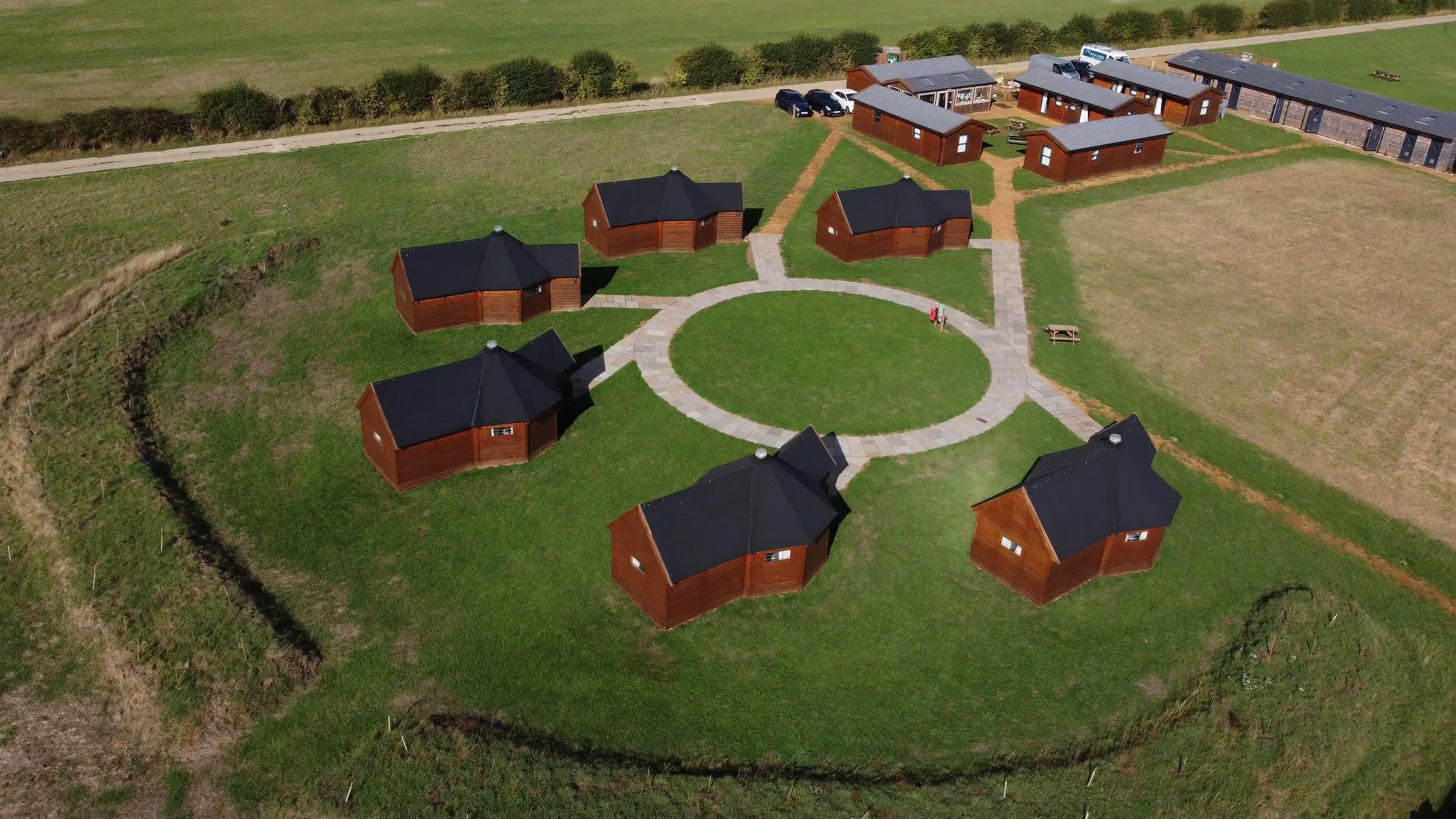 The timber yurt village from above, surrounded by open fields